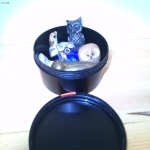 Kleines schwarzes Tontöpfchen gefüllt mit lustigen Tierfiguren